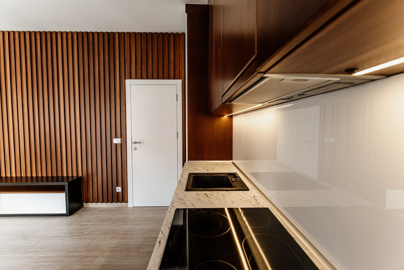 Timber slats and cabinetry meeting a pale stone counter in a restrained kitchen interior.